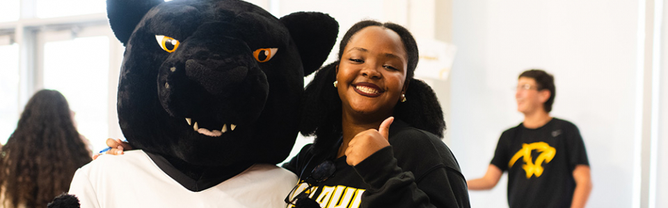 An Adelphi student with the Adelphi University panther mascot.