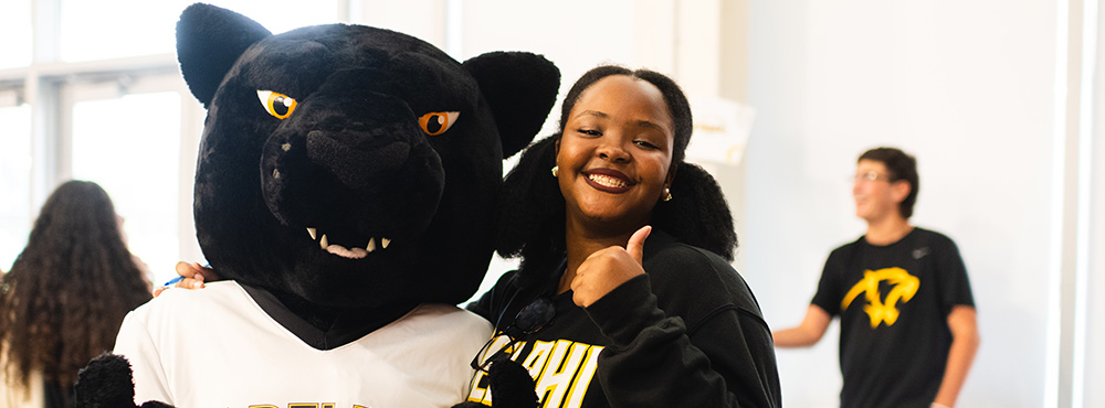 An Adelphi student posing with the Panther mascot